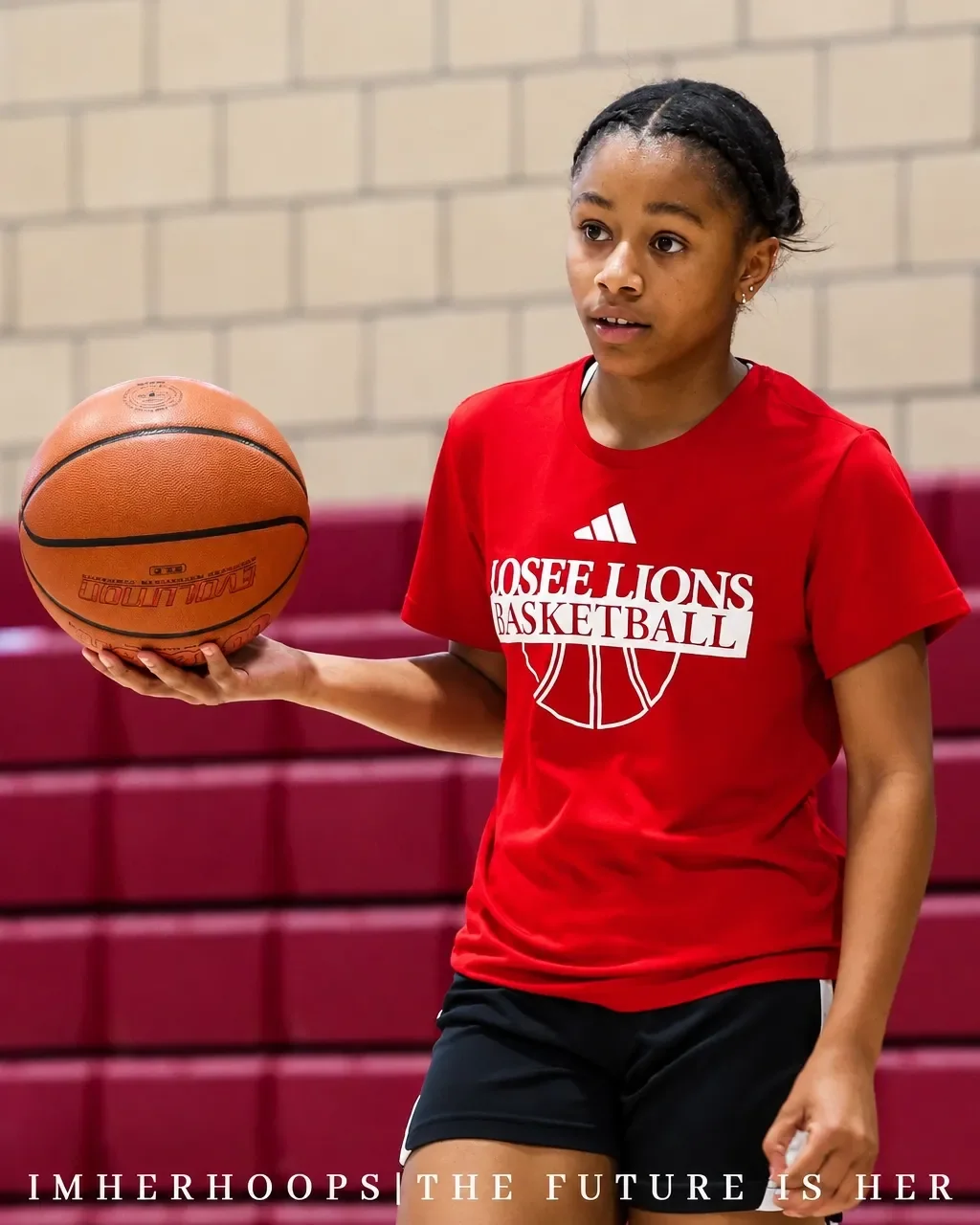 Jordynn Riggins holding a basketball in a red Somerset Losee Basketball shirt during training